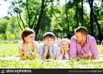 Happy family having weekend in summer park. Picnic in garden