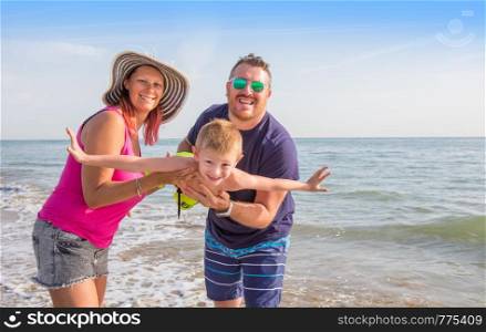 happy family holding boy hands on beach