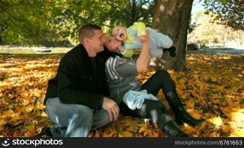 Happy Family Holding Their Child in the autumn park