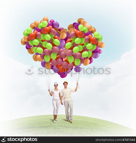 Happy family. Image of young couple holding bunch of colorful balloons