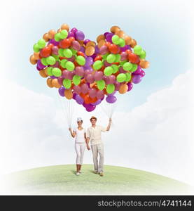 Happy family. Image of young couple holding bunch of colorful balloons