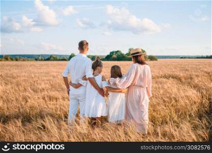 Happy family in a wheat field at summer day. Happy family playing in a wheat field