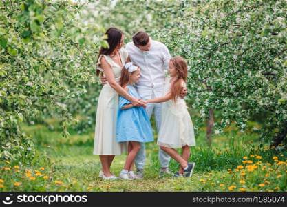 Happy family in blooming garden on beautiful spring day on Easter. Adorable family in blooming cherry garden on beautiful spring day