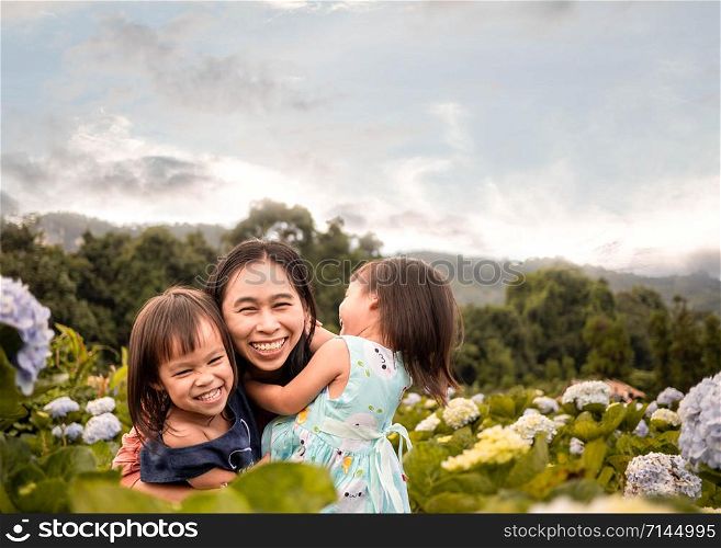 Happy family in hydrangea garden over trees with mountains background under blue sky in summer day.