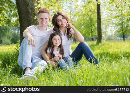 Happy family in park. Happy family with man, woman and child leaning on tree in city park