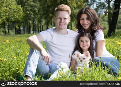 Happy family in park. Happy family with man, woman and child sitting on grass in city park