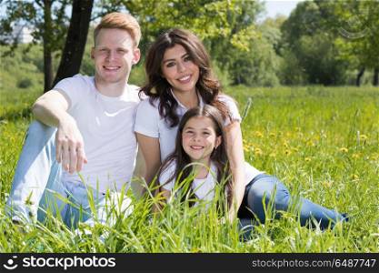 Happy family in park. Happy family with man, woman and child sitting on grass in city park
