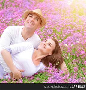 Happy family in spring park lying down on flowers meadow and looking up in the sky, having fun together, romantic lifestyle concept