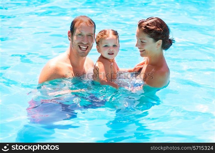 Happy family in swimming pool with baby girl in summer vacation