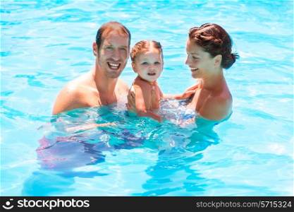 Happy family in swimming pool with baby girl in summer vacation