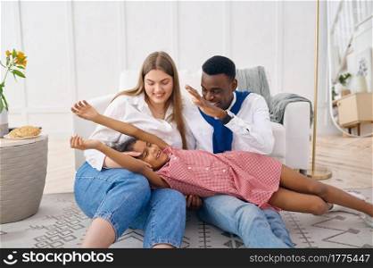 Happy family leisures in living room. Mother, father and their daughter poses at home together, good relationship. Happy family leisures in living room at home