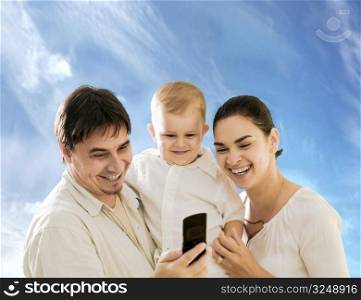 Happy family looking at mobile phone sceen outdoor.