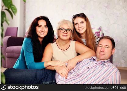 Happy family looking at the camera. Family at home relaxing on carpet. Indoors, lifestyle