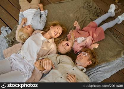 Happy family lying on blankets, top view, summer camping. Parents with children travel in camp car, nature and forest on background. Campsite adventure, travelling lifestyle. Happy family lying on blankets, top view, camping