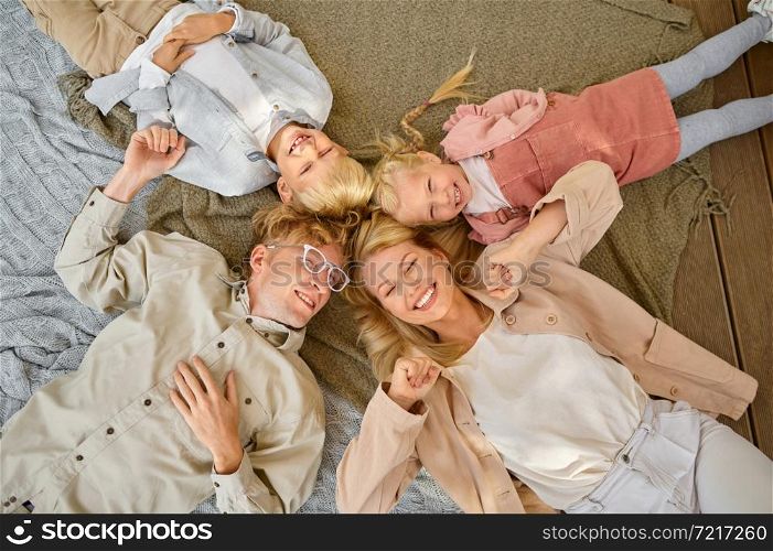 Happy family lying on blankets, top view, summer camping. Parents with children travel in camp car, nature and forest on background. Campsite adventure, travelling lifestyle. Happy family lying on blankets, top view, camping