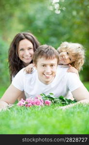 Happy family lying on grass in spring park against blurred green background