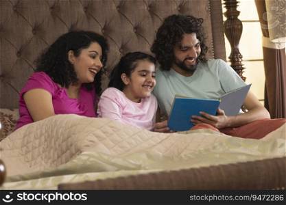 Happy family members watching photo album together in bedroom 