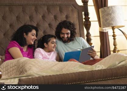 Happy family members watching photo album together in bedroom 