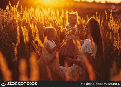 happy family, mom and two daughters. Mother and daughter on sunset in the forest. family concept. Mother plays with her daughter on the street in the park at sunset.. happy family, mom and two daughters. Mother plays with her daughter on the street in at sunset. family concept