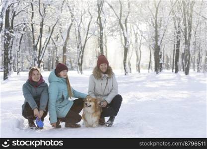 happy family - mom, daughters and corgi dog in winter park
