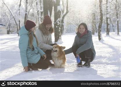 happy family - mom, daughters and corgi dog in winter park 