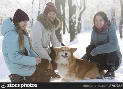 happy family - mom, daughters and corgi dog in winter park
