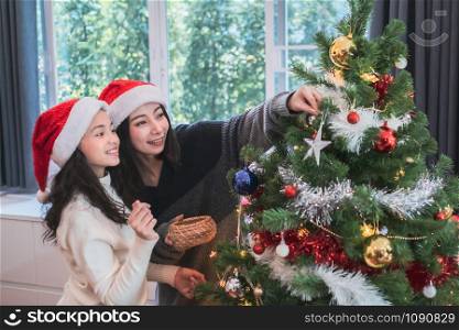 happy family, mother and daughter help to decorate gift, toy, present box together at christmas day night in living room that decorated with christmas tree for christmas festival day