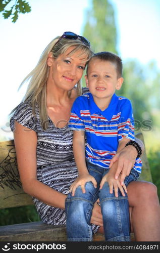 Happy family mother and her child boy on bench in park enjoy the summer