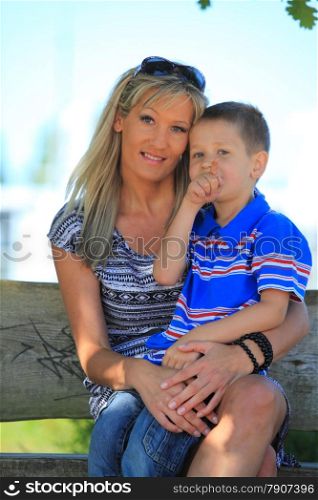 Happy family mother and her child boy on bench in park enjoy the summer