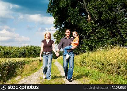 Happy family (mother, father and kid) having a walk in the nature