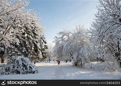 Happy family (mother with small boy and girl) in winter snow covered city park path