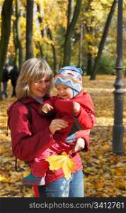 Happy family (mother with small boy) in golden autumn city park