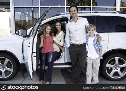 Happy family next to white car