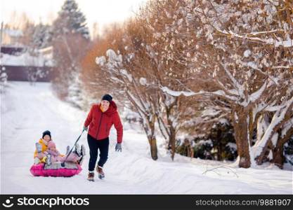 Happy family of father and kids riding on a tube and having fun outdoors in winter. Family of dad and kids vacation on Christmas eve outdoors