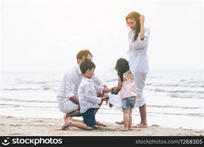 Happy family of father, mother and kids goes vacation on a tropical sand beach in summer.