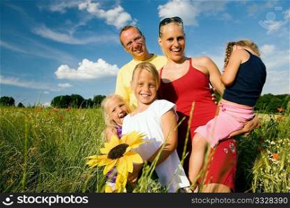 Happy family of five standing in the grass with and flowers together - metaphor for love