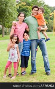 Happy family of five standing together in the park, outdoors