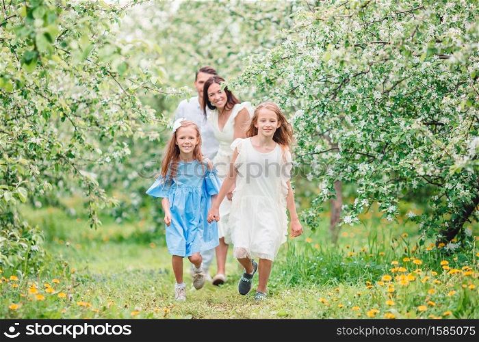 Happy family of four in blooming garden. Adorable family in blooming cherry garden on beautiful spring day