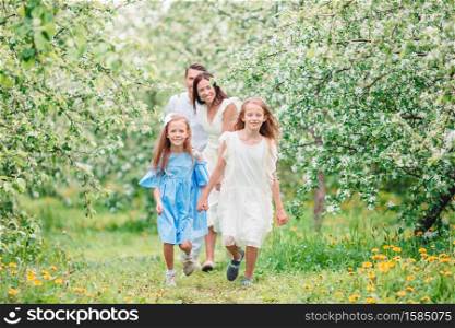 Happy family of four in blooming garden. Adorable family in blooming cherry garden on beautiful spring day