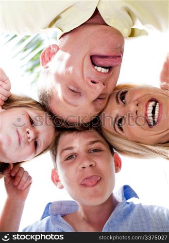 Happy family of four in huddle making weird faces and smiling at camera