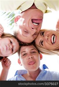 Happy family of four in huddle making weird faces and smiling at camera