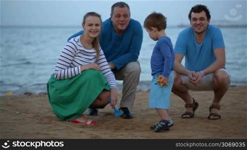 Happy family of four looking to the camera at the seaside in the evening