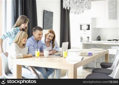 Happy family of four using laptop at home