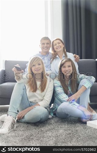 Happy family of four watching TV together at home