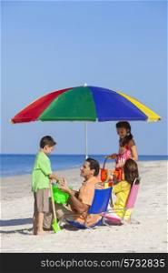 Happy family of mother &amp; father, parents daughter &amp; son children having fun in deckchairs under an umbrella on a sunny beach