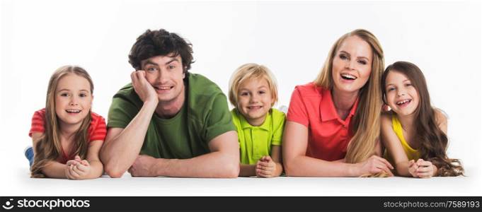 Happy family of parents and three children laying on floor isolated on white background. Happy family laying on white