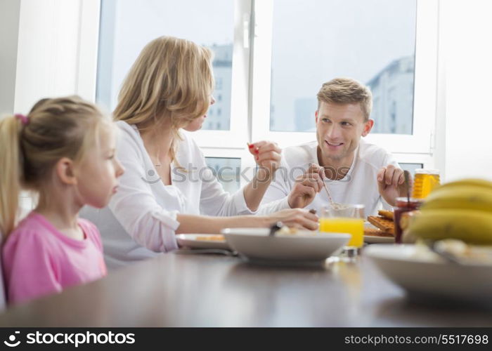 Happy family of three having breakfast at table