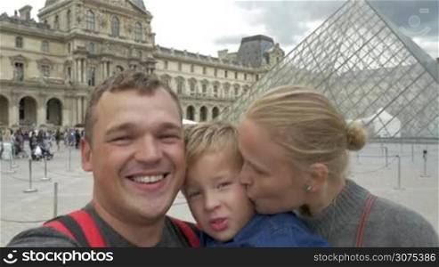 Happy family of tourists taking selfie video while visiting Louvre Museum in Paris, France