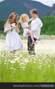 Happy family on big camomile mountain meadow. Emotional, love and care scene.