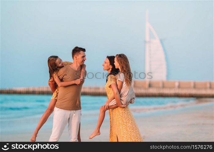 Happy family on the beach at summer vacation with Burj Al Arab on background in Dubai, UAE. United Arab Emirates famous tourist destination.. Happy family on the beach during summer vacation